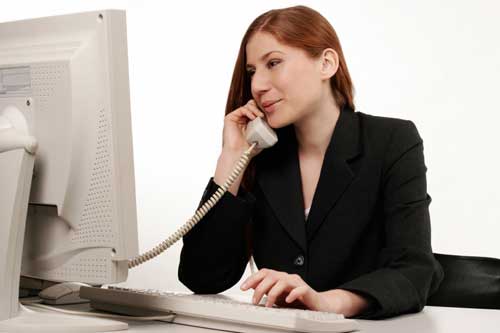 young woman on the phone in front of a computer