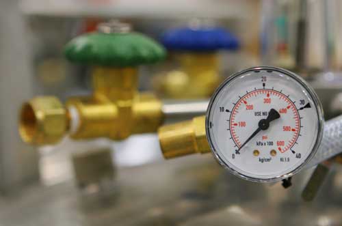 A pressure guage is shown in the foreground and measures the performance of plumbing equipment