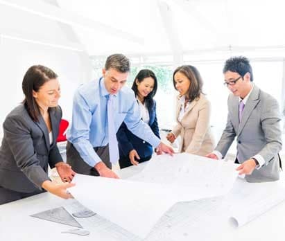 A group of men and women in an office reviewing a set of plans