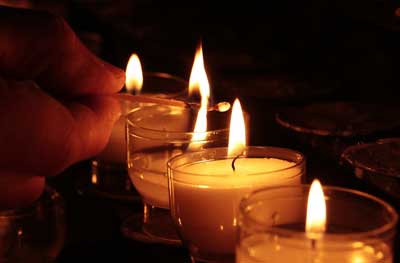 someone lighting a row of tea lights