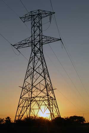 an electrical tower with the sun behind it