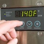 a person's fingers touching control panel of tankless water heater