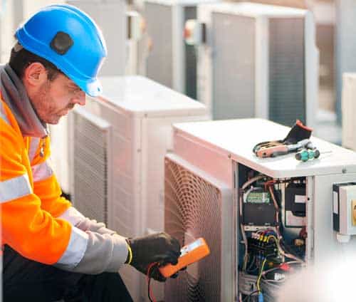 An HVAC technician checking the readings of a cooling system