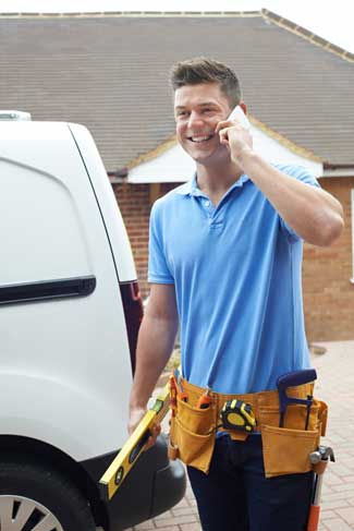 A building contractor talking on cell phone standing next to white van