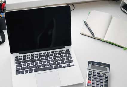 desk with laptop, notebook and calculator