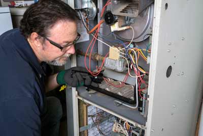 service technician performing maintenance on old furnace