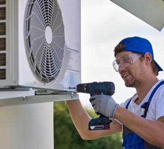 Man using drill to install or repair air conditioning unit