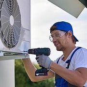 Man with a drill repairing or installing an air conditioning system