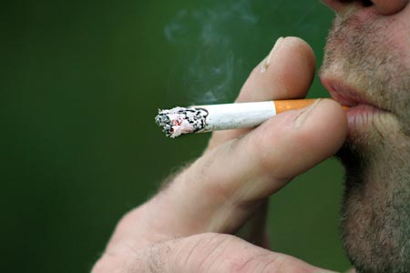 Part of someone's face showing cigarette smoking
