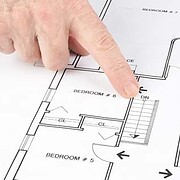 A finger pointing to an area of a home's floor plan.